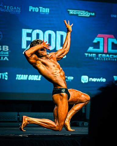 Jake Cawfield posing on stage at his bodybuilding show